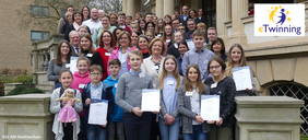 Kindergruppe auf Schultreppe mit Urkunden in der Hand